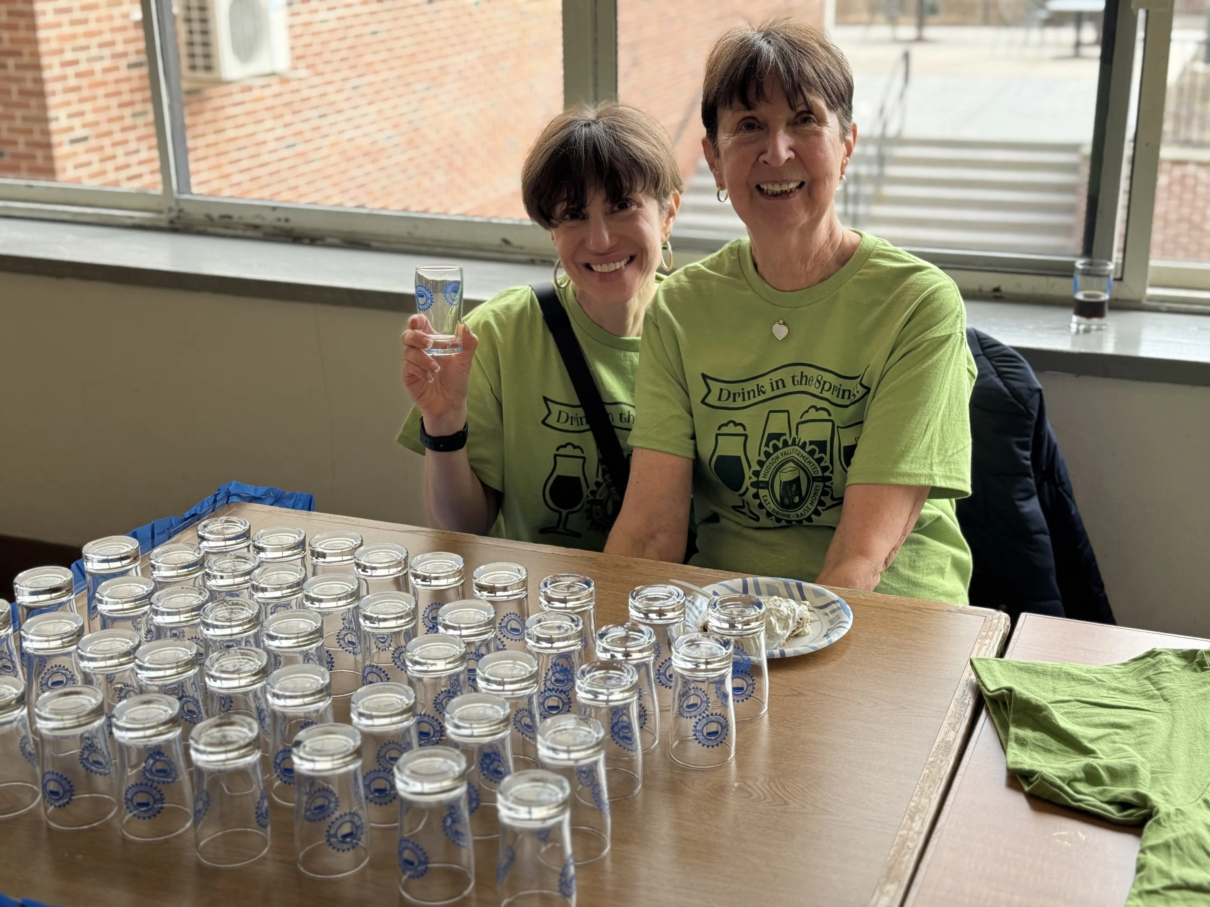 Two volunteers in event T-shirts with trays of tasting glasses