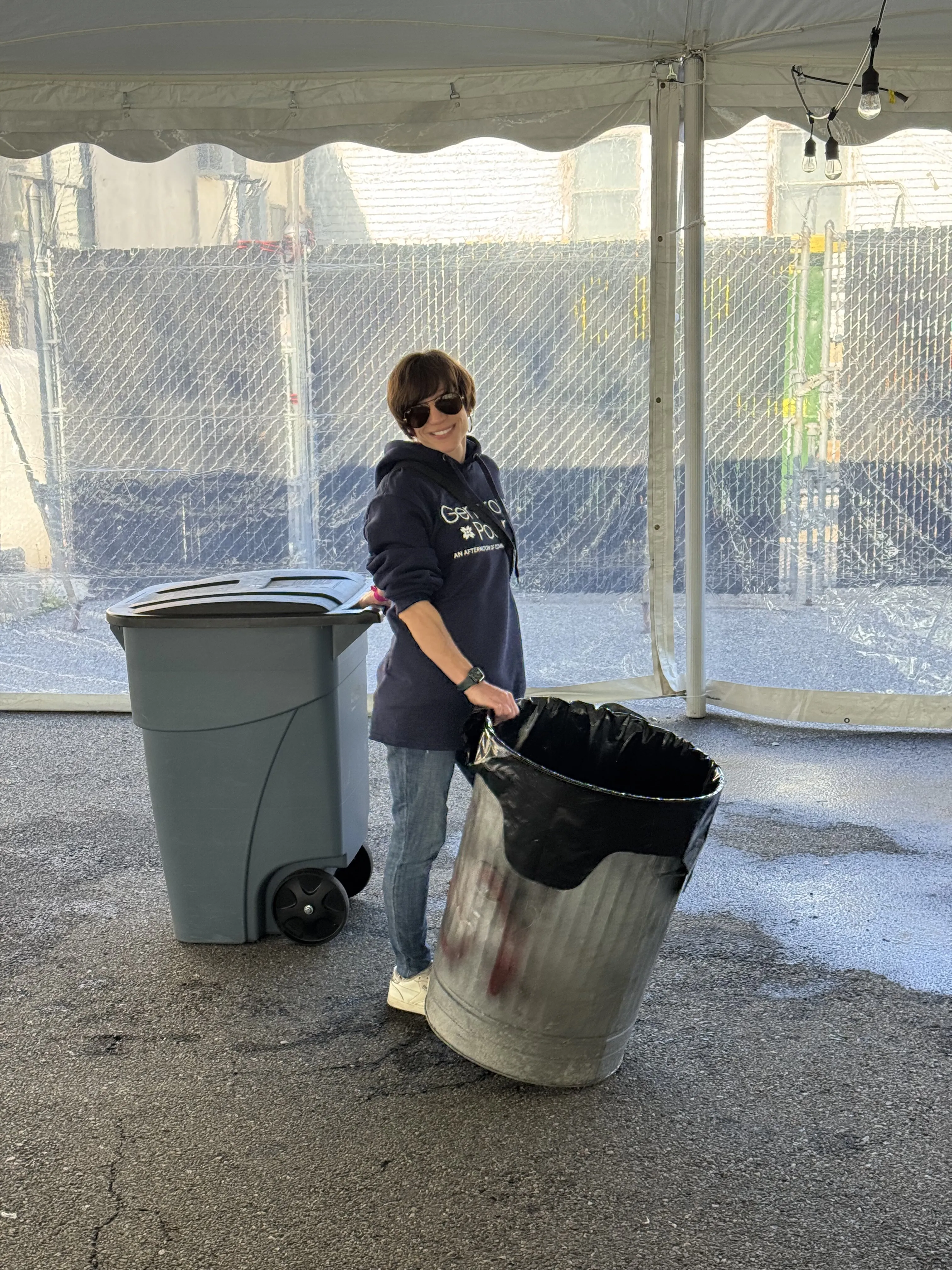 Margaret hauling a trash can under the Generous Pour tent